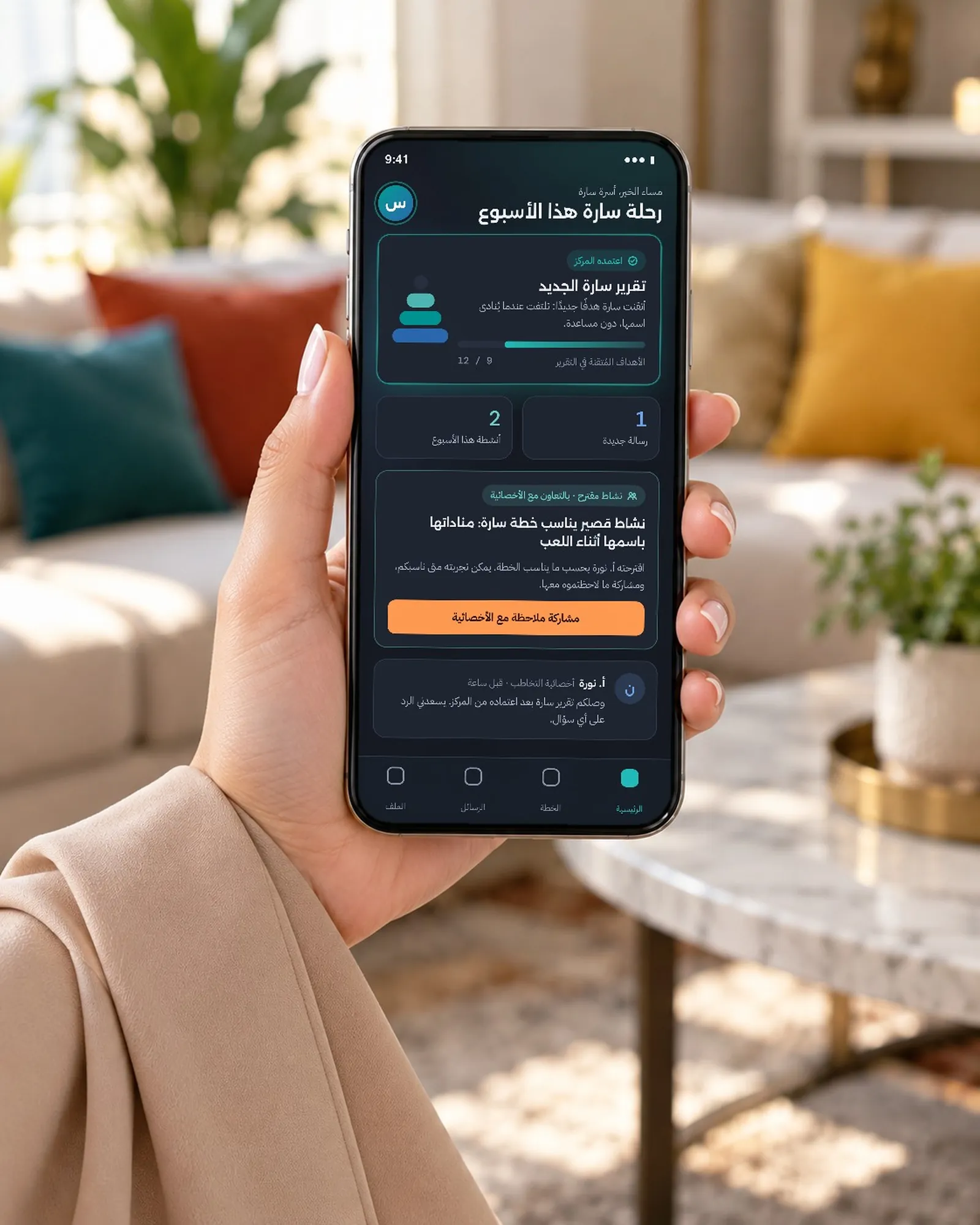 يد أم في المنزل تحمل هاتفًا يعرض تطبيق الأسرة: رحلة سارة هذا الأسبوع، وفيه تقرير سارة الجديد بعد اعتماده من المركز.